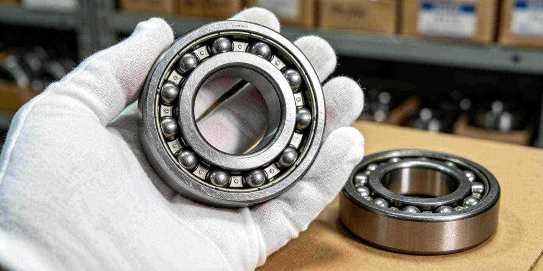 Micro close-up of 6204 deep groove ball bearing held by gloved hand, top 10 bearing suppliers 2022 review, precision industrial manufacturing